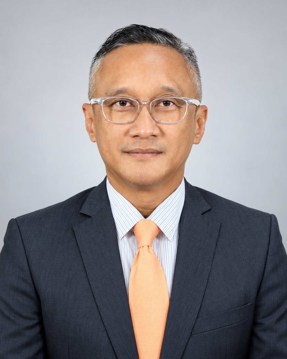 Azly Basarian wearing a navy suit and orange tie